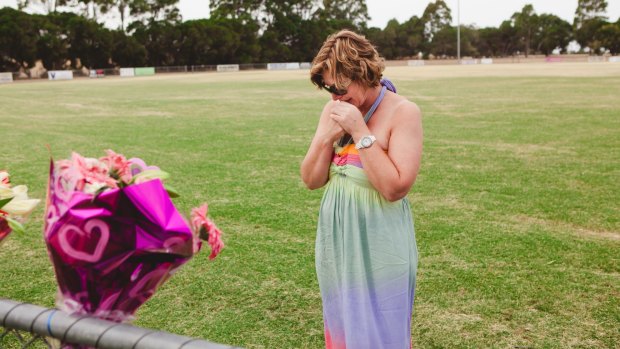 Luke Batty's mother, Rosie Batty, at Tyabb oval reading cards well wishers left following the death of her son in early 2014.