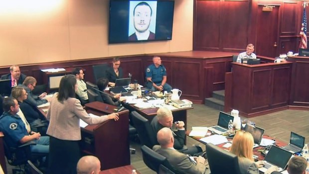 Defence attorney Tamara Brady, standing, questions Robert Holmes, top right, the father of James Holmes, on screen, during the sentencing phase of James' trial.