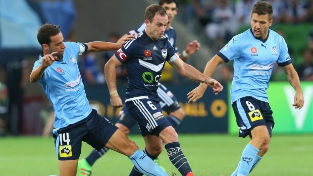 Leigh Broxham of the Victory is tackled by Alex Brosque of Sydney FC.