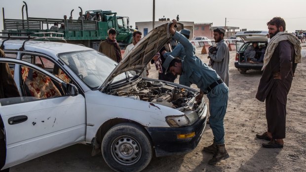 An Afghan National Police officer searches a car for drugs, in Zaranj, Afghanistan.