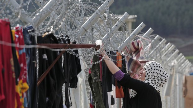 A Syrian refugee hangs clothes to dry on a barbed-wired fence at a camp for Syrian refugees in Islahiye, in Turkey.