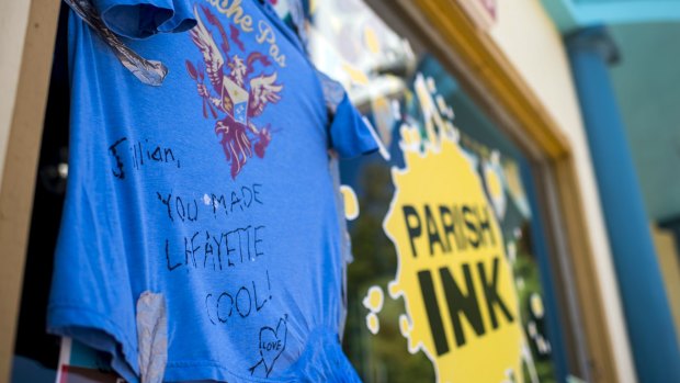 A shirt with a message dedicated to shooting victim Jillian Johnson hangs on the storefront window of Johnson's store Parish Ink in downtown Lafayette.