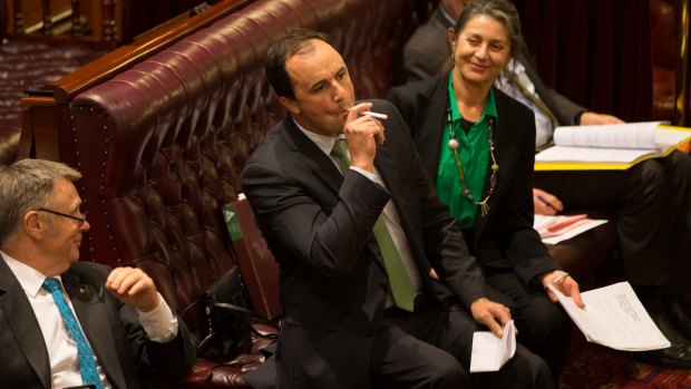 Greens MP Jeremy Buckingham lights an e-cigarette in the NSW Upper House to show how lax the laws are that govern the devices.