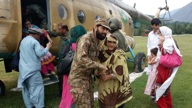 Pakistan army officers help stranded people evacuate from flood-hit areas in Chitral, Pakistan, on Thursday.