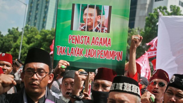 Protesters shout slogans as they hold up a placard depicting Jakarta governor Basuki Tjahaja Purnama behind bars in Jakarta.