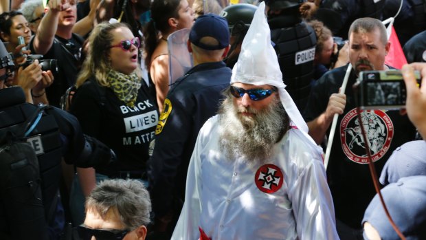 Members of the KKK are escorted by police past a large group of counter-protesters  in Charlottesville.