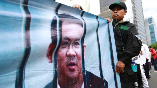 A Muslim protester displays a banner depicting Jakarta governor Ahok behind bars outside court on the day of his trial hearing.
