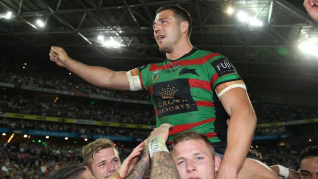 Missed: Rabbitohs enforcer Sam Burgess is chaired off the field by his brothers George and Thomas after the 2015 grand final win over Canterbury.