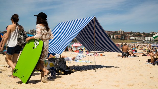 A beach shelter, with hazardously long guy ropes, takes a large space on a crowded Bondi Beach in Sydney. 