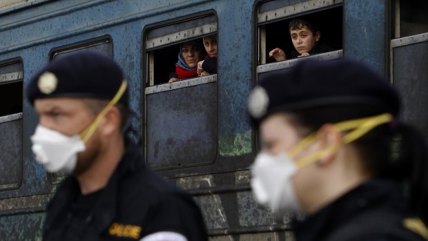 Refugees aboard a train bound for Serbia watch Czech Republic police officers maintaining order at the transit centre for refugees, near southern Macedonia's town of Gevgelija on Sunday. 