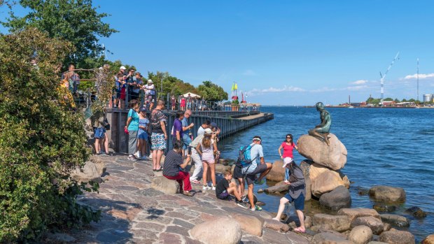 Tourists posing for pictures by The Little Mermaid in Copenhagen.
