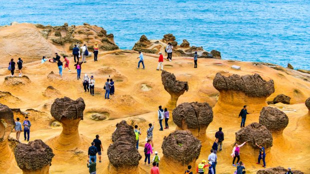 Many tourists walk around the stone shapes at Yehliu Geopark.