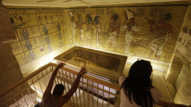 Tourists look at the tomb of King Tutankhamun as it is displayed in a glass case at the Valley of the Kings in Luxor, Egypt. 