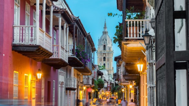 Street view of Cartagena, Colombia after sunset with cathedral visible in the background.
