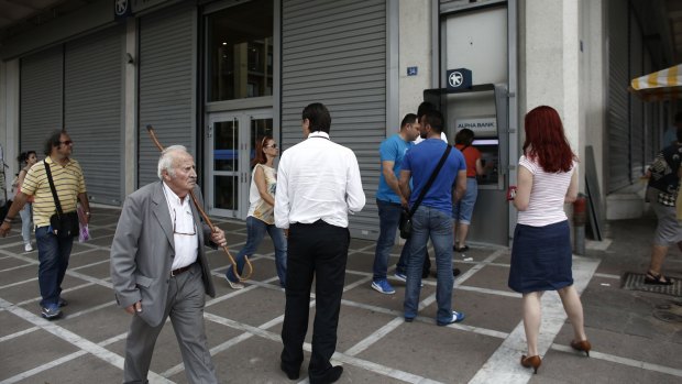 Bank customers queue to withdraw cash from an ATM in Athens, Greece, on Friday.
