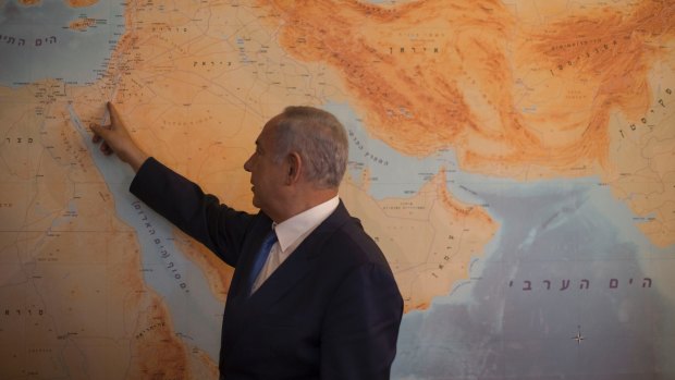 Israeli Prime Minister Benjamin Netanyahu points at Israel on the map in his Jerusalem office.