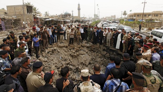 Residents and Iraqi security forces gather around a hole caused by a suicide car attack at a market in Khan Bani Saad, north-east of Baghdad, on Friday. .