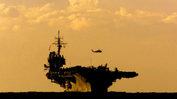 A helicopter hovers above US aircraft carrier USS Kitty Hawk as it enters Sydney Harbour.