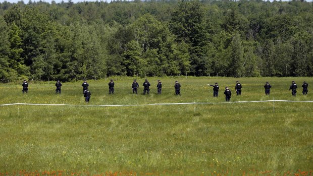 Law enforcement officers walk in a field along Route 3 on Saturday.