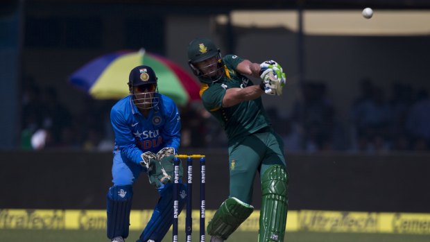 South African captain A.B. de Villiers clobbers a six as his Indian counterpart, M.S. Dhoni, watches.