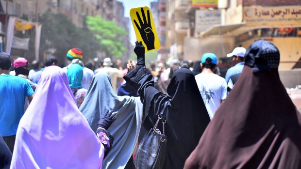Female supporters of the Muslim Brotherhood gesture and hold up a sign picturing a hand with four fingers, a symbolic reminder of the deadly crackdown on Muslim Brotherhood supporters in 2013.