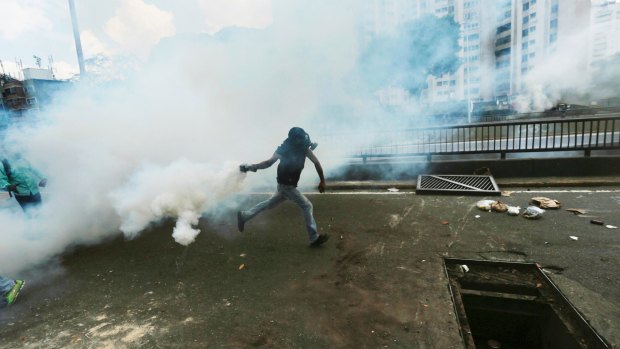 A demonstrator throws back a tear gas canister launched by security forces during a protest in Caracas.