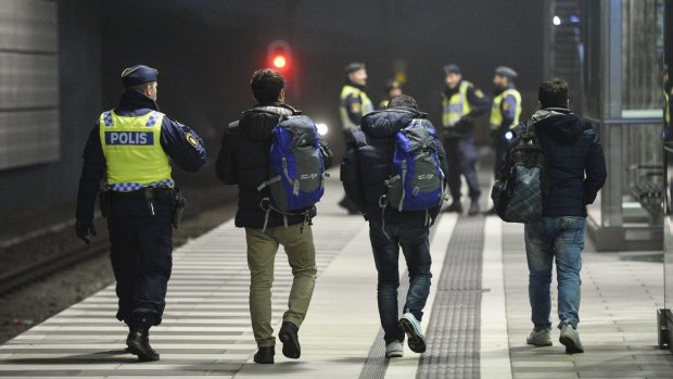 The police escort three men from a train at Hyllie station outside Malmo, Sweden.  Interior Minister Anders Ygeman says Sweden could deport between 60,000 and 80,000 asylum-seekers in coming years. 