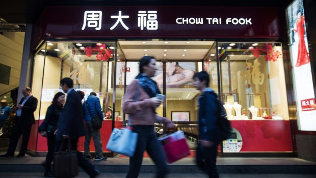 Pedestrians walk past a Chow Tai Fook Jewellery Group store in the Central district of Hong Kong.
