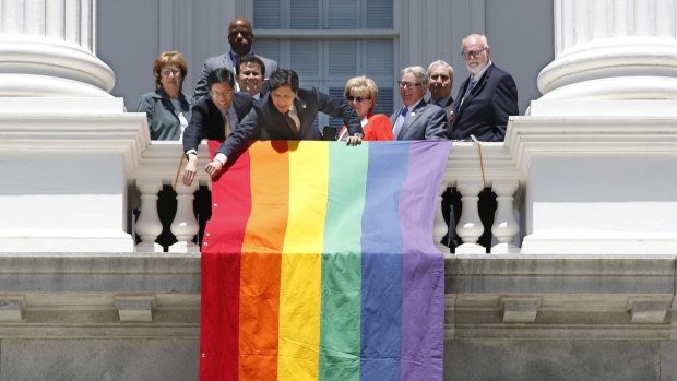 Members of the Senate unfurl the gay pride flag on the balcony of the Capitol in California.