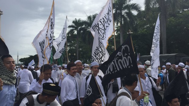 Protester hold flags bearing the Islamic testament of faith - one of them upside down - at the rally in Jakarta.