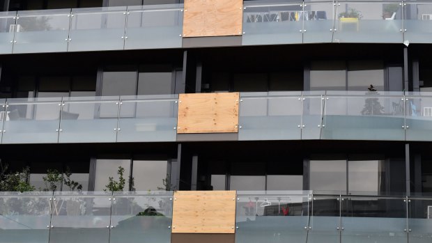 Balconies in this Melbourne apartment building have been patched up with wood following multiple glass explosions.