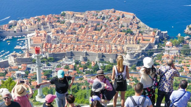  Tourists looking out over panorama view of old town Dubrovnik.