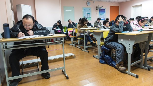 A fifth-grader's parent tries to solve problems set in his child's exam, at at a school in Shanghai, China.
