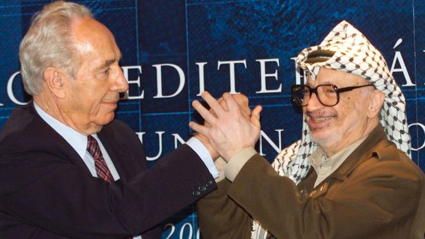 Palestinian leader Yasser Arafat, right, clasps hands with then Israeli Foreign Minister Shimon Peres, left, at a special session of the Euro Mediterranean Project in 2001.