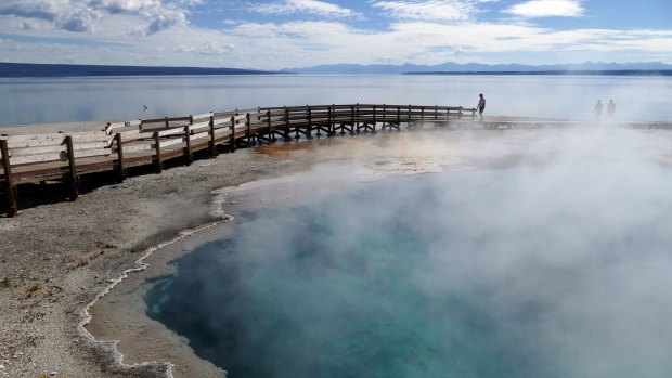 Visitors on a boardwalk that extends into the Black Pool at the West Thumb Geyser Basin, Yellowstone National Park, Wyoming.