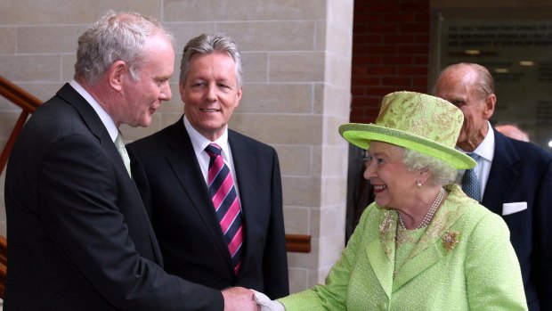 Queen Elizabeth shakes hands with  former IRA commander and Deputy First Minister Martin McGuinness watched by First Minister Peter Robinson in Belfast in 2012.