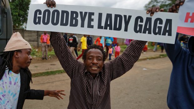 A protester demanding Robert Mugabe's resignation carries a placard referencing the excesses of Mugabe's wife, Grace.