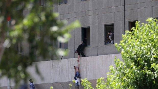 A man hands a child to a security guard from Iran's parliament building in Tehran after an attack on the complex on Wednesday.