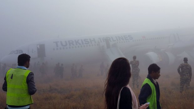 Eerie: Rescue and military personnel surround a Turkish Airlines jet after it skidded off the runway on landing at Kathmandu airport.