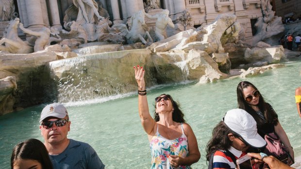 A tourist throws a coin in the Trevi Fountain in Rome.