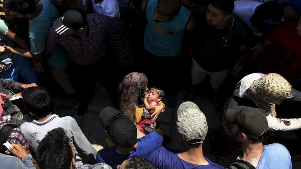 Syrian men form a safety passage for women following clashes during a registration procedure at the Kos stadium.