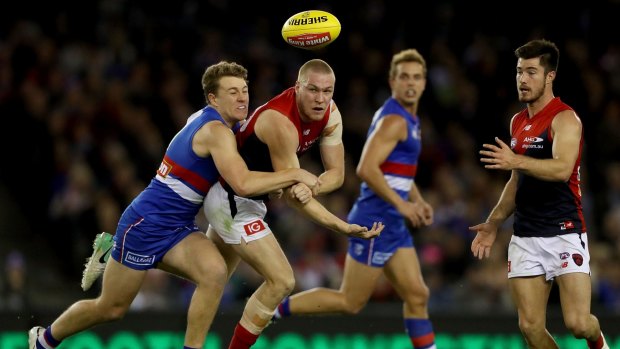 Out and about: Demon Tom McDonald handballs clear of Jackson Macrae of the Bulldogs during round 13 at Etihad Stadium.