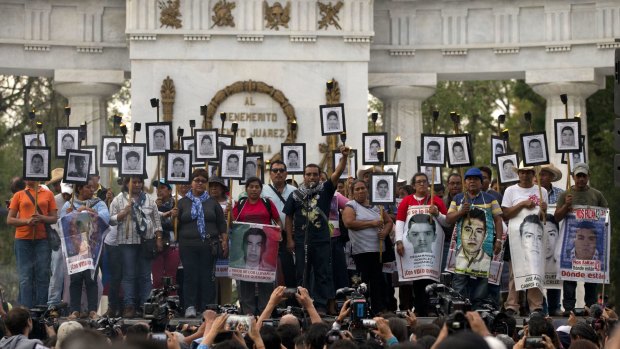 Family members of 43 missing teacher students carry their pictures last week.