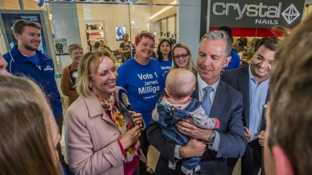 Leader of the opposition Jeremy Hanson holds Annabel, Alistair Coe's daughter, in the Gungahlin shopping centre.