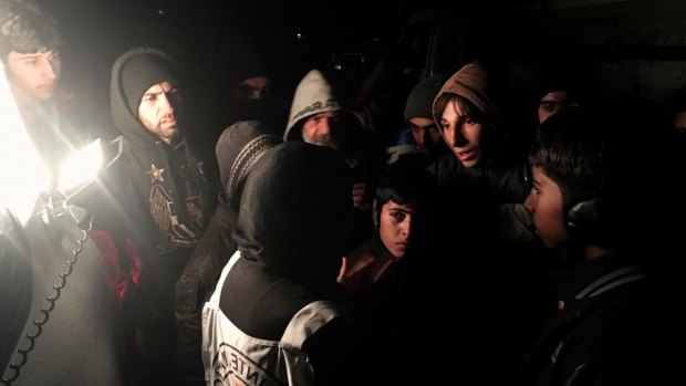 The head of the Red Cross delegation in Syria, Marianne Gasser, speaks to residents as they gather around an aid convoy. 