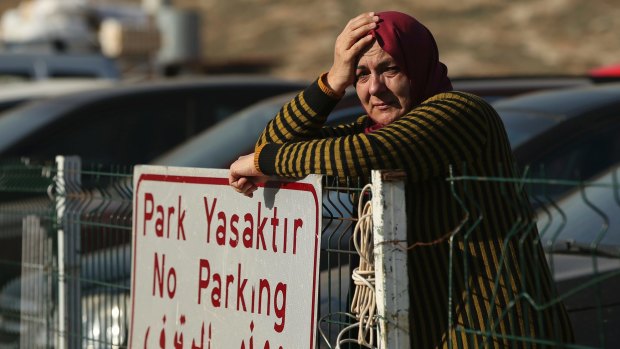 A Syrian woman waits for other family members to cross into Turkey as the evacuation of fighters and civilians from the last remaining opposition stronghold in Aleppo resumed after days of delays