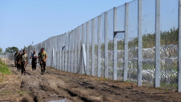 Hungarian soldiers walk along the border fence near the town of Morahalom, Hungary, on Monday.