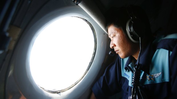 Military officer Nguyen Tran looks out from a Vietnam Air Force aircraft during an earlier mission to find MH370.
