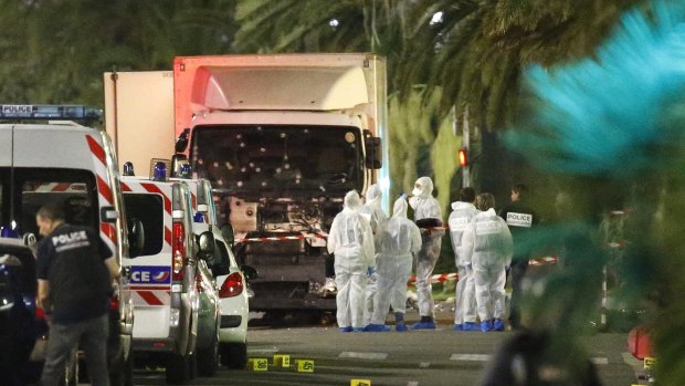 French police forces and forensic officers stand next to a truck that ran into a crowd in Nice.