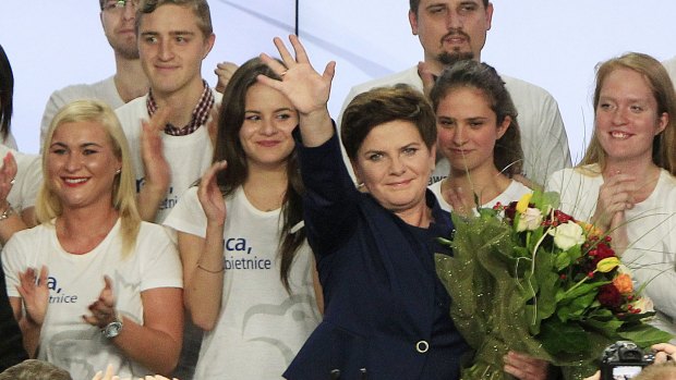 The candidate for prime minister, Beata Szydlo, waves after her Eurosceptic party defeats the pro-EU Civic Platform.
